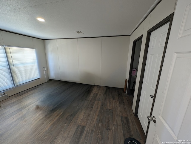 empty room with dark wood-type flooring, a textured ceiling, and ornamental molding