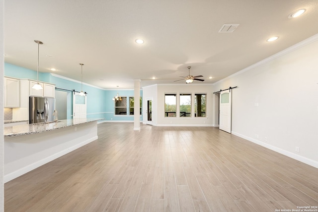 unfurnished living room with a barn door, light hardwood / wood-style floors, and crown molding