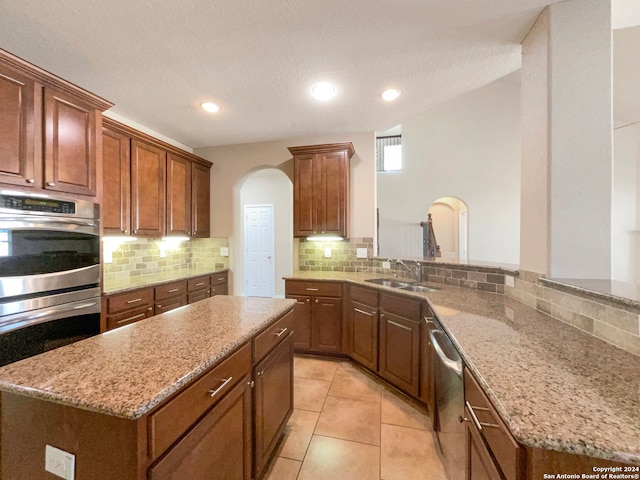 kitchen with appliances with stainless steel finishes, tasteful backsplash, a textured ceiling, a center island, and light tile patterned flooring