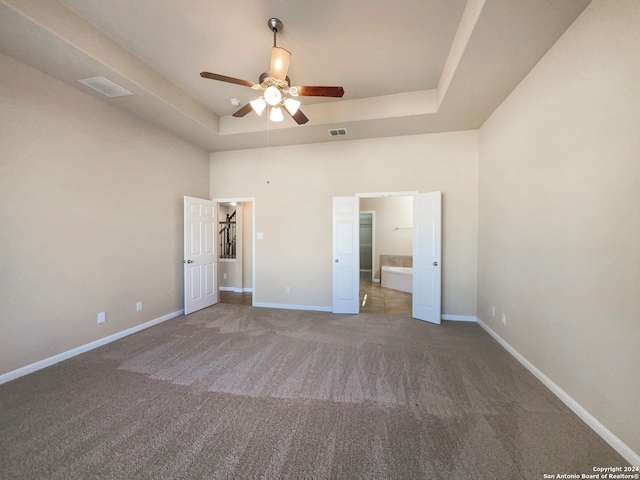 unfurnished bedroom with a tray ceiling, ceiling fan, and carpet