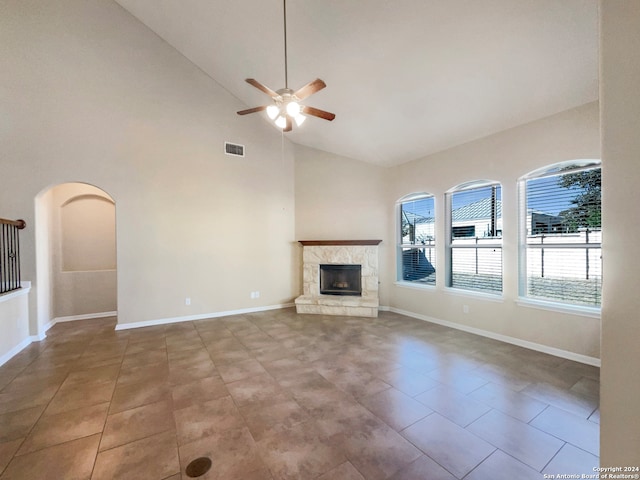 unfurnished living room with a fireplace, light tile patterned floors, high vaulted ceiling, and ceiling fan