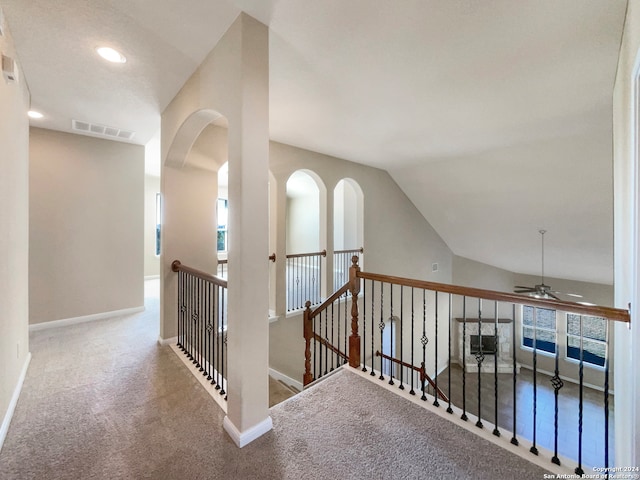 hallway with carpet floors and vaulted ceiling