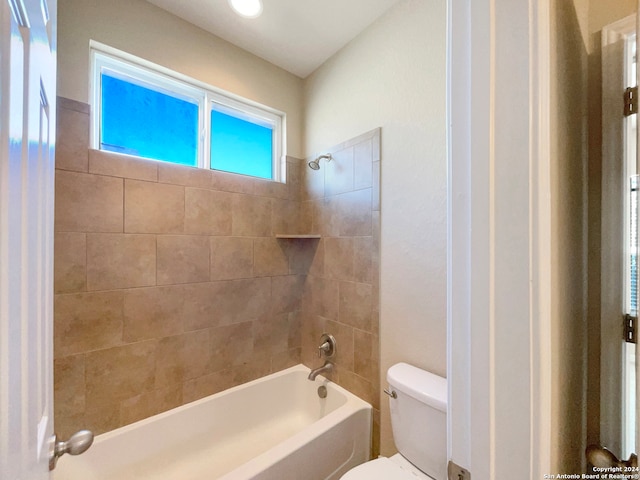 bathroom featuring tiled shower / bath combo and toilet