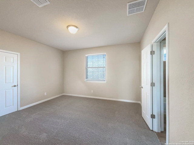 carpeted spare room featuring a textured ceiling