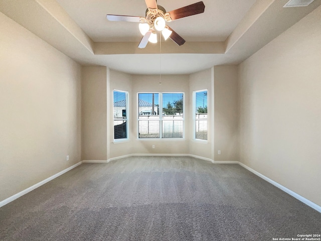 unfurnished room featuring a tray ceiling, ceiling fan, and carpet floors