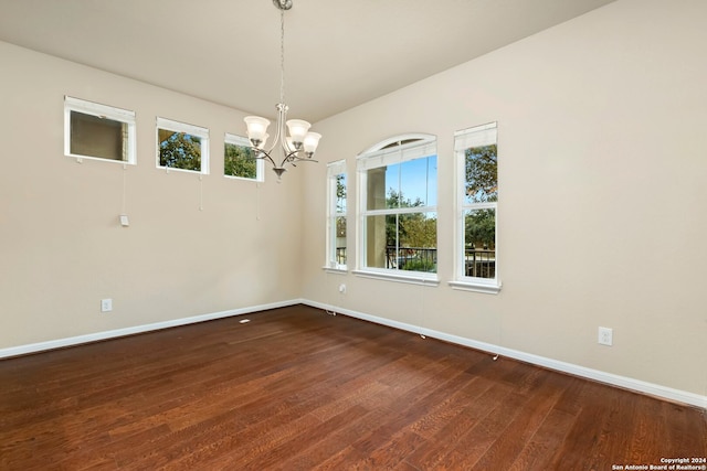 empty room with a notable chandelier and dark wood-type flooring