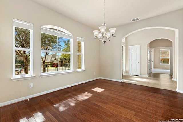 unfurnished dining area with hardwood / wood-style flooring and a notable chandelier