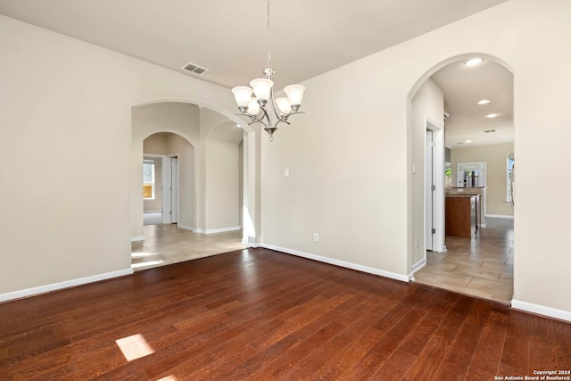 empty room featuring hardwood / wood-style flooring and an inviting chandelier