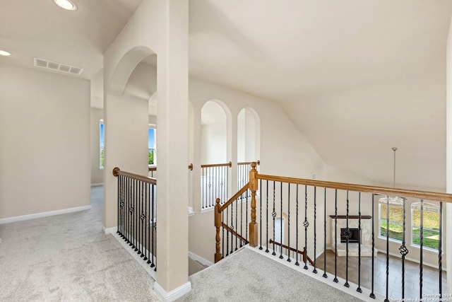 hallway with light carpet and vaulted ceiling