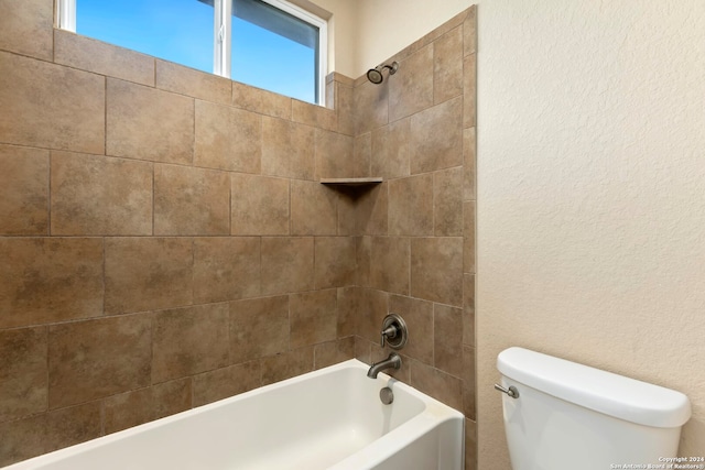 bathroom featuring toilet and tiled shower / bath