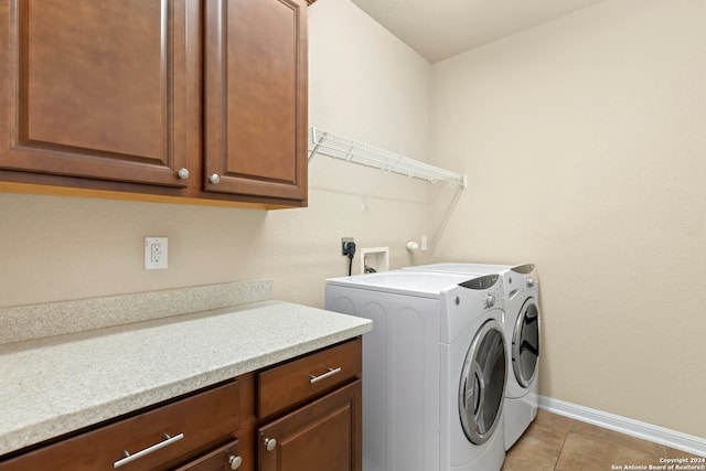 clothes washing area with washing machine and dryer, light tile patterned floors, and cabinets