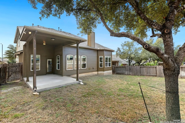 back of house featuring a lawn and a patio area