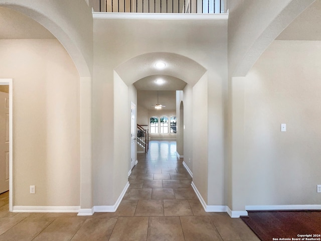 hallway with tile patterned floors and a high ceiling