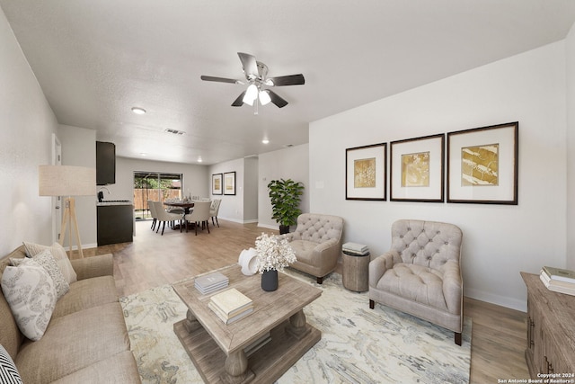 living room featuring a textured ceiling, light hardwood / wood-style floors, and ceiling fan