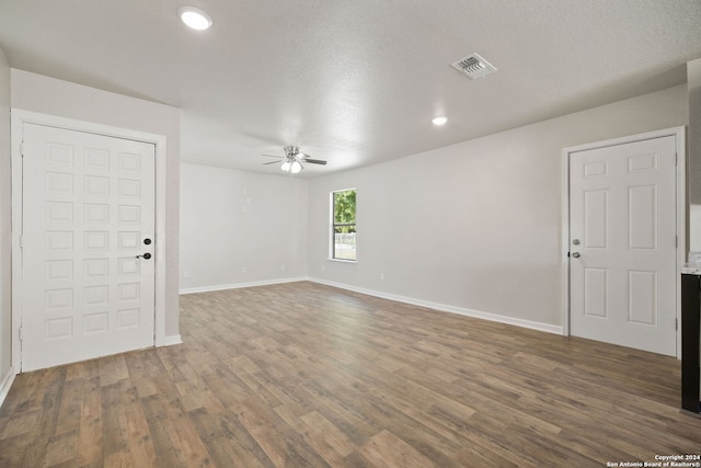 unfurnished room with a textured ceiling, ceiling fan, and dark wood-type flooring