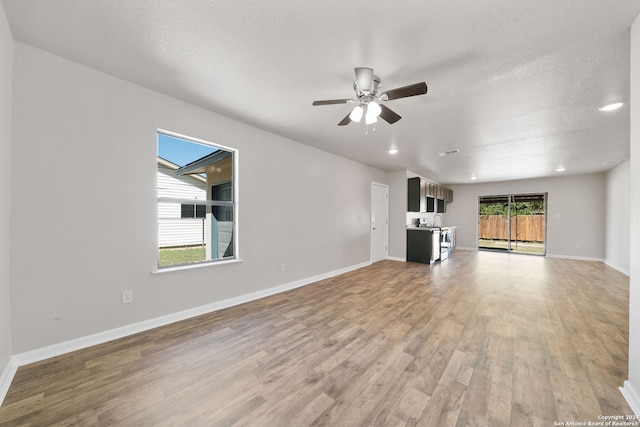 unfurnished living room featuring a textured ceiling, light hardwood / wood-style floors, and ceiling fan