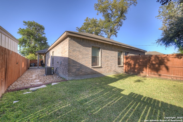 back of property with central AC unit and a lawn