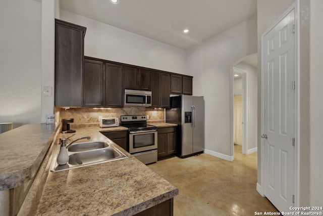 kitchen featuring kitchen peninsula, sink, dark brown cabinets, and appliances with stainless steel finishes