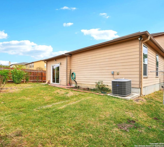 rear view of house featuring central AC unit and a lawn