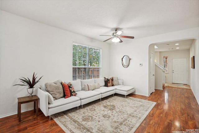 living room with ceiling fan and dark wood-type flooring