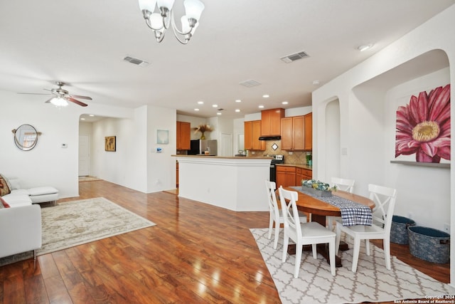 dining room with ceiling fan with notable chandelier and light hardwood / wood-style floors