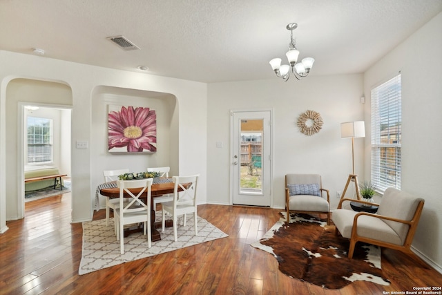 dining space featuring wood-type flooring, a textured ceiling, and a notable chandelier