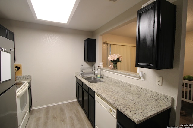 kitchen featuring light stone counters, sink, light hardwood / wood-style floors, and white appliances