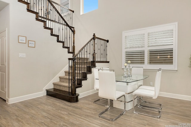 dining room with hardwood / wood-style flooring and a towering ceiling