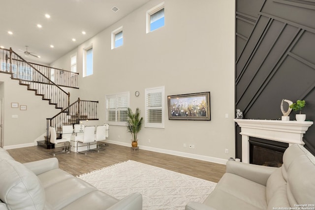 living room with ceiling fan, a high ceiling, and hardwood / wood-style flooring