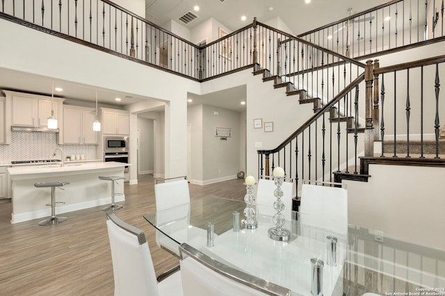 dining space with light hardwood / wood-style flooring, a high ceiling, and sink