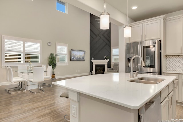 kitchen featuring white cabinets, a kitchen island with sink, stainless steel appliances, and hanging light fixtures