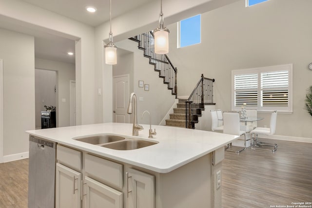 kitchen with hanging light fixtures, sink, a center island with sink, dishwasher, and plenty of natural light