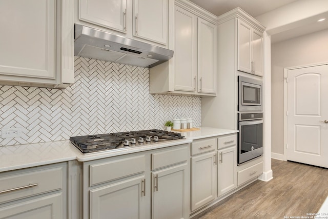 kitchen featuring decorative backsplash, appliances with stainless steel finishes, and light wood-type flooring