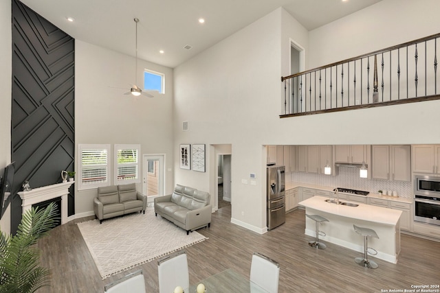 living room featuring light hardwood / wood-style flooring, a healthy amount of sunlight, a high ceiling, and sink