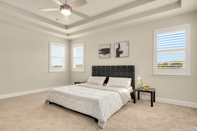 bedroom with carpet flooring, a raised ceiling, and ceiling fan