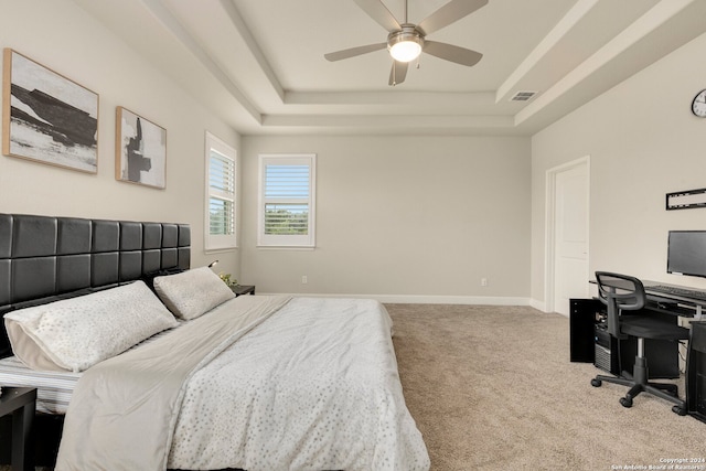 carpeted bedroom with ceiling fan and a raised ceiling