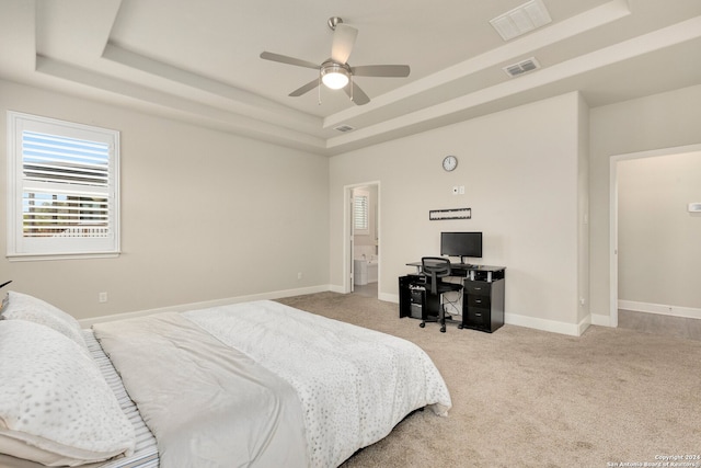 carpeted bedroom with ceiling fan and a tray ceiling