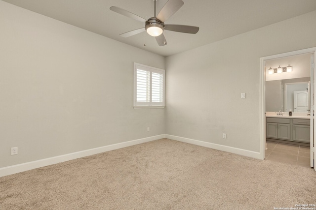 unfurnished bedroom with ensuite bathroom, sink, ceiling fan, and light carpet