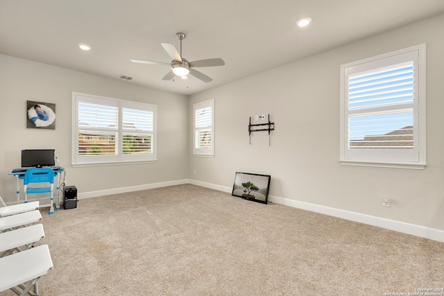 interior space with a wealth of natural light, ceiling fan, and light carpet