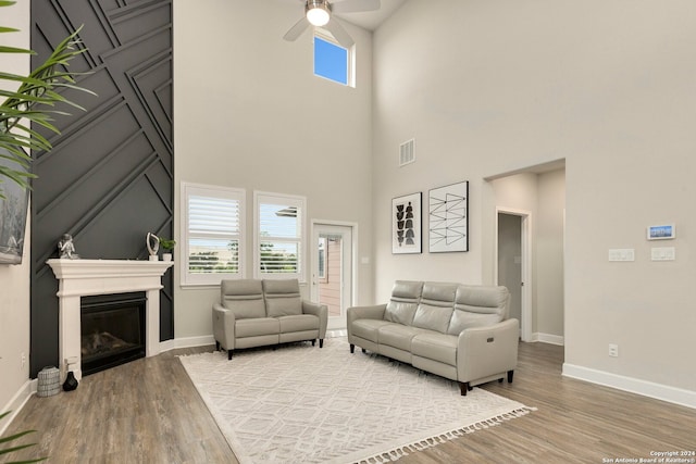 living room featuring wood-type flooring, ceiling fan, and a high ceiling