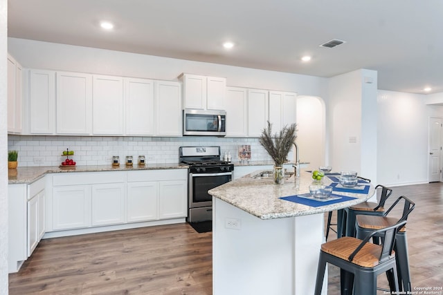 kitchen with appliances with stainless steel finishes, white cabinetry, and hardwood / wood-style floors