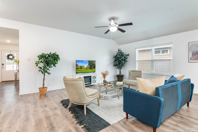 living room with ceiling fan, light wood-type flooring, a fireplace, and vaulted ceiling