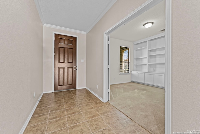 entryway featuring light colored carpet, a textured ceiling, and ornamental molding