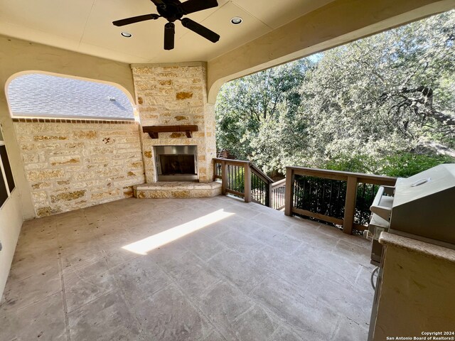 view of patio with an outdoor stone fireplace, ceiling fan, and exterior kitchen