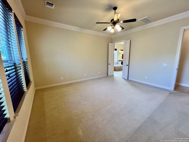 empty room featuring light carpet, ceiling fan, and ornamental molding