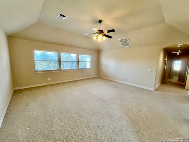 carpeted empty room with ceiling fan and lofted ceiling