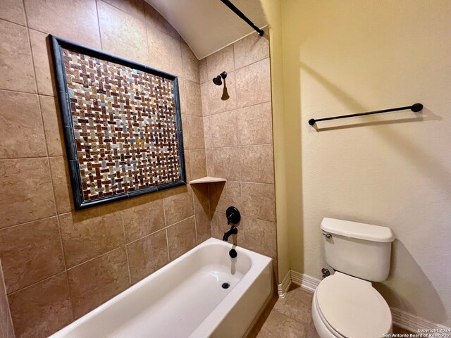 bathroom featuring tile patterned flooring, toilet, tiled shower / bath, and lofted ceiling