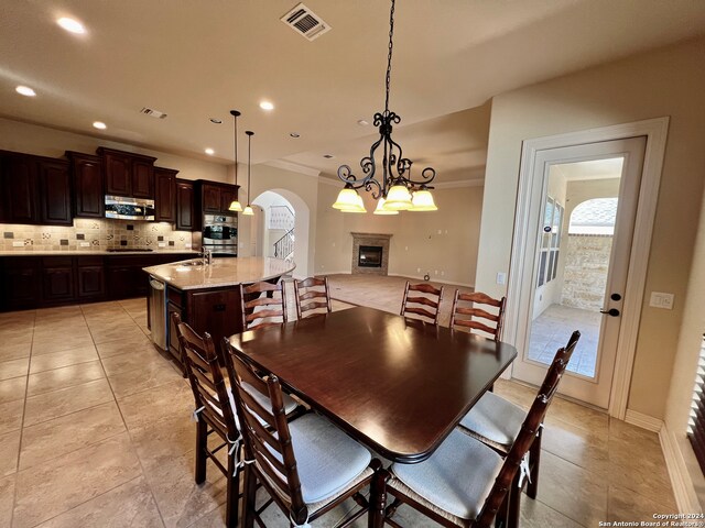 dining room featuring light tile patterned floors, a notable chandelier, ornamental molding, and sink