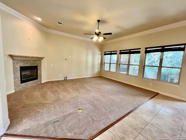 unfurnished living room featuring crown molding, a fireplace, ceiling fan, and light colored carpet