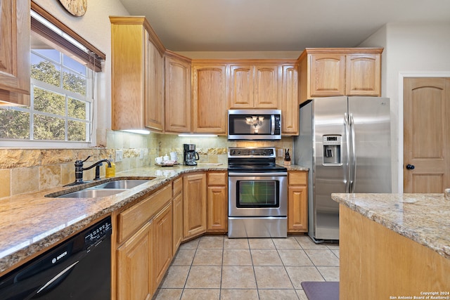 kitchen featuring light stone countertops, appliances with stainless steel finishes, backsplash, sink, and light tile patterned flooring